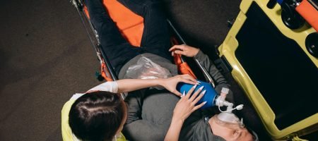 Paramedic providing emergency care to a patient using a bag valve mask in an ambulance.